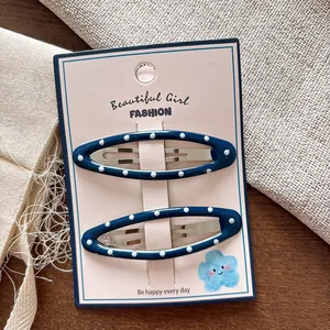 Dettaglio di due fermagli per capelli BB blu a pois su carta decorativa confezionata