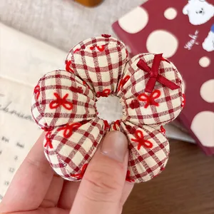 Macro detail of a red plaid flower-shaped scrunchie with cute bow embroidery for kids