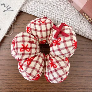 Detailed macro view of a red checkered flower hair tie with delicate embroidery bows