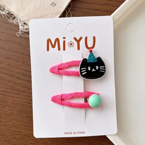 Detail of pink fabric-wrapped hair clips with black cat embroidery and green bead details