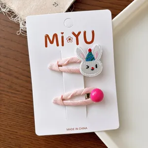 Detail of pink embroidered rabbit hair clip and round bead hairpin on display card