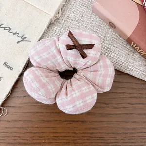 Close-up of pink and white checkered fabric flower hair scrunchie with small brown ribbon bow