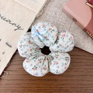 Close-up of floral fabric scrunchie with a small blue bow on a rustic wooden background