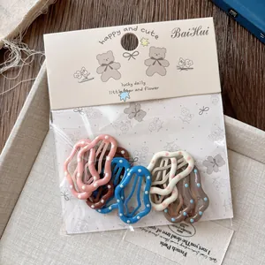 Détail de barrettes à cheveux à pois en forme de vagues aux couleurs variées avec emballage