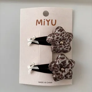 Detail of leopard print flower hair clips with velvet wrapping and faux pearl center