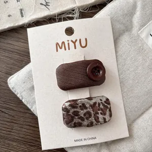 Detail of leopard print star hair clips and brown twill button barrettes on card