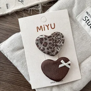Close-up of leopard print and brown satin heart hair clips on white card set
