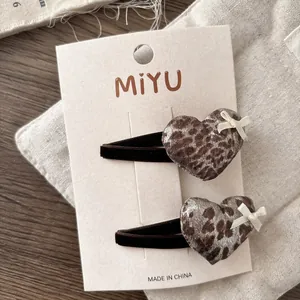 Detail of leopard print heart hair clips with ribbon bows on brand card packaging