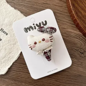 Gros plan sur la barrette chat 3D rembourrée avec un nœud à carreaux et des perles