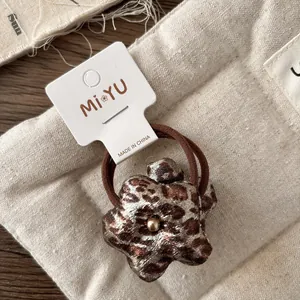 Detail of leopard print hair scrunchie with center pearl on soft quilted background