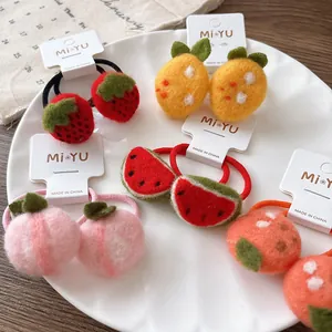 Vue détaillée des chouchous faits main en laine feutrée avec motifs fraise et pastèque