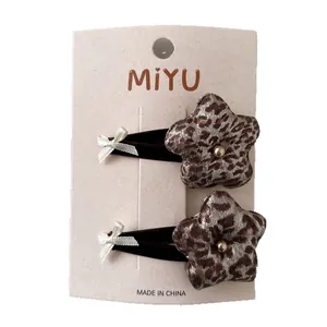 Two-piece leopard print star hair clips with gold beads and white bows on display card