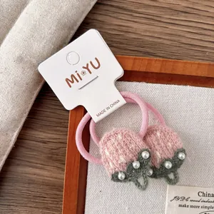Gros plan d'élastiques à cheveux fraises en tricot rose avec détails de perles