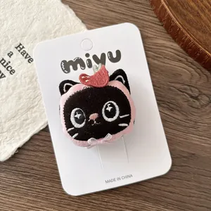 Détail de la pince à cheveux chat en peluche avec nœud rose et cœur sur carte