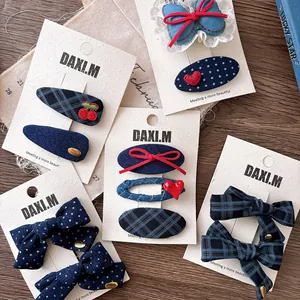 Close-up of navy plaid bow hair clips and cherry embroidery on white display card