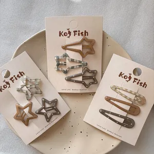 Brown star and drop-shaped hair clips set with plaid pattern on a ceramic tray