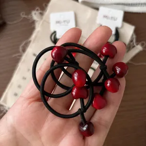 Dettaglio dell'elastico per capelli con ciondoli a ciliegia rossa e corda nera