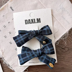 Detail of navy blue plaid bow hair clips with gold Hand Made charms on display card