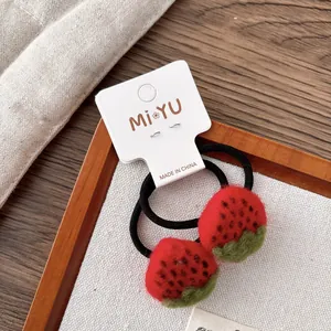 Gros plan d'élastiques à cheveux fraises en feutre rouge faits main sur carte