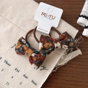 Détail de chouchous à nœuds en tissu floral avec bandes élastiques sur table en bois