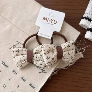 Vue rapprochée d'élastiques à cheveux avec nœuds beiges à motifs floraux sur bois