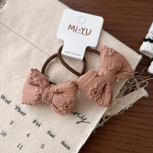 Détail de deux chouchous roses avec broderie florale et étiquette de marque MiYU