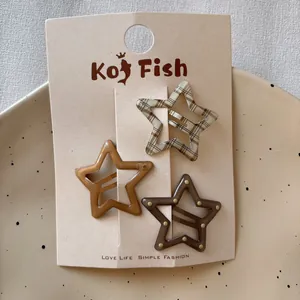 Three-piece set of star-shaped hair clips in brown tones on branded card packaging