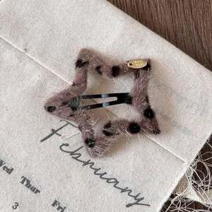 Star-shaped plush leopard print hair clip with black metal BB clip and gold tag detail