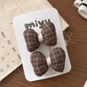 Détail des barrettes à cheveux à nœuds à carreaux beige et marron sur carte de support
