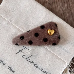 Detail of plush leopard print hair clip with gold heart on cream canvas background