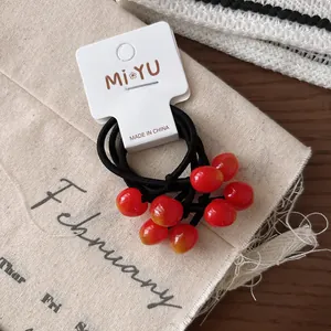 Dettaglio di elastici per capelli a forma di ciliegia per bambine su carta regalo