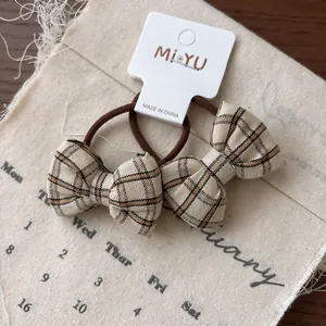 Détail de chouchous à nœud à carreaux beige et noir sur fond de tissu en coton vintage