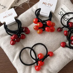 Dettaglio di elastici per capelli con perline ciliegia rosse su cartellini MiYU