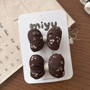 Détail de deux barrettes à nœuds marron foncé à motifs floraux sur une carte support