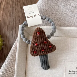 Detail of handmade crochet mushroom hair tie with velvet beads on a grey elastic band