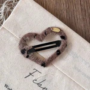 Detail of heart-shaped leopard plush hair clip with a gold Hand Made metal tag