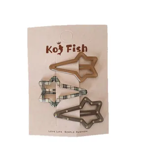 Three brown star-shaped hair clips in solid, checkered, and dotted patterns on card