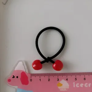 Elastico per capelli con ciliegie rosse e righello di misurazione su piano