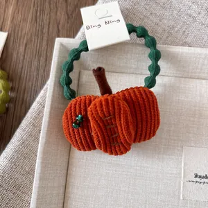 Detailed view of handmade pumpkin hair tie with orange corduroy and green elastic band