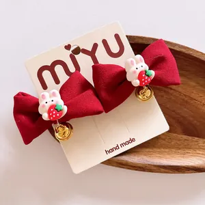 Détail de barrettes nœuds rouges avec figurines de lapin et petites clochettes dorées