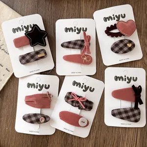 Close-up of pink velvet bow hair clips and vintage plaid patterns on card display