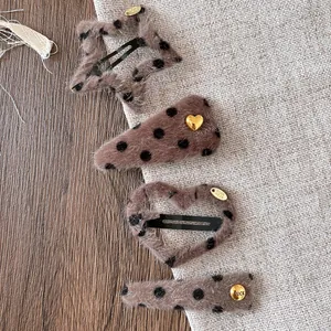 Detail of four leopard print plush hair clips with gold metal tags on linen fabric
