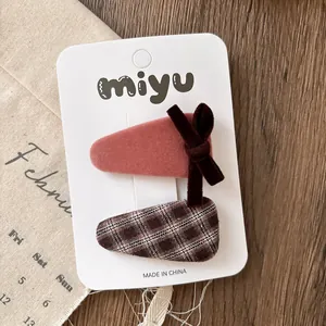 Detail of pink velvet and brown plaid bow hair clips on white display card
