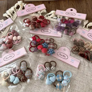 Detalle de varios coleteros infantiles de tela con lazos y estampados de corazones