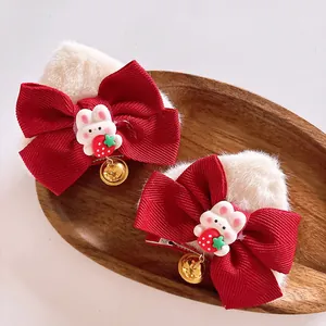 Détail de pinces à cheveux oreilles de chat en peluche avec nœuds rouges et clochettes