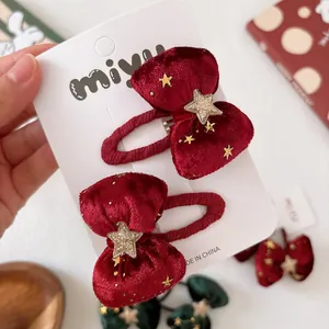 Fermagli per capelli natalizi in velluto rosso con stelle dorate su scheda di presentazione