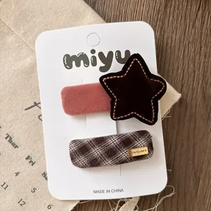 Close-up of brown velvet star hairpin and plaid clip with metal tag on display card
