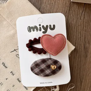 Detail of red heart and brown checkered hair clips on white display card