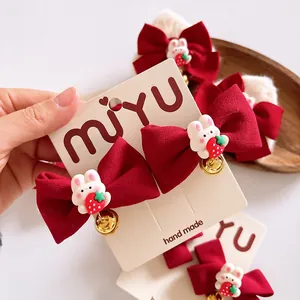 Détail de pinces à cheveux à nœuds rouges avec lapins, fraises et petites cloches dorées