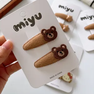 Set of two brown teddy bear embroidery hair clips for girls on a white brand card display